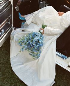 a bride and groom sitting in the back of an old car with flowers on it