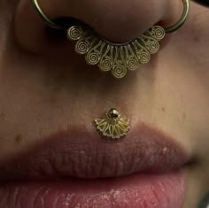 a close up of a person's nose with gold jewelry on it