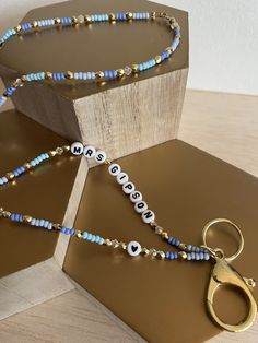 a pair of blue beaded necklaces sitting on top of a wooden block next to a pair of scissors