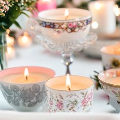 candles are lit on a table with flowers