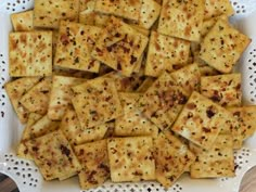 a white plate topped with lots of crackers on top of a wooden table