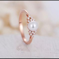 a pearl and diamond ring sitting on top of a table