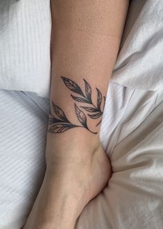 a woman's foot with a tattoo on it and leaves coming out of the top