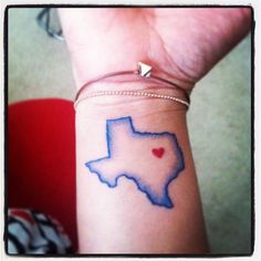 a woman's arm with a tattoo on it that has a heart in the shape of texas