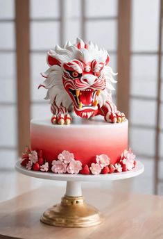 a red and white cake with a dragon decoration on it's top is sitting on a table