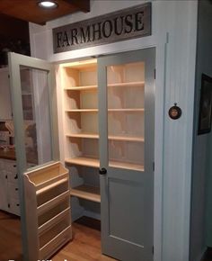 an open closet with shelves and drawers in the corner, next to a door that says farmhouse