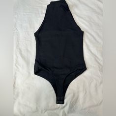 a black one piece swimsuit laying on top of a white sheeted bed spread