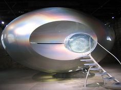 a large metal object sitting on top of a white floor next to a ladder in front of it