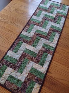 a table runner made with green and brown quilts on top of a wooden table