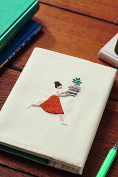 a notebook with a drawing of a woman holding a pine cone on top of it