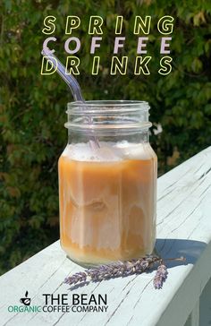 a jar filled with liquid sitting on top of a wooden table next to trees and bushes