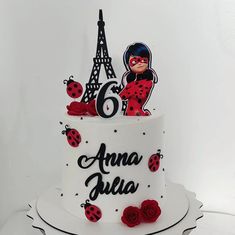 a birthday cake decorated with ladybugs and the eiffel tower