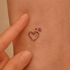 a small heart tattoo on the side of a woman's left arm and wrist