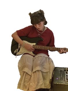 a woman sitting on top of a suitcase with a guitar in her hand and wearing a red shirt