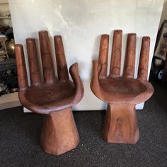 two wooden chairs sitting next to each other on top of a carpeted floor in front of a white wall