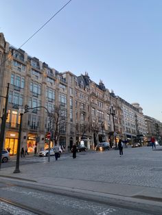 people are walking on the street in front of some tall buildings with lots of windows