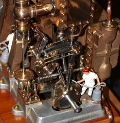 a close up of a toy man working on an old fashioned machine with lots of metal parts