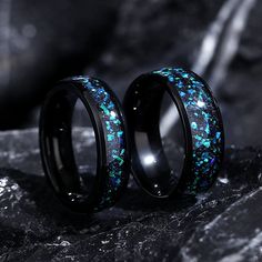 two black rings with blue and green glitters on them