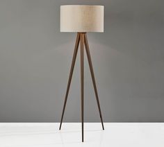 a tripod floor lamp with a white shade on it's top and wooden legs