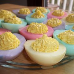 deviled eggs with yellow frosting are on a glass plate, ready to be eaten