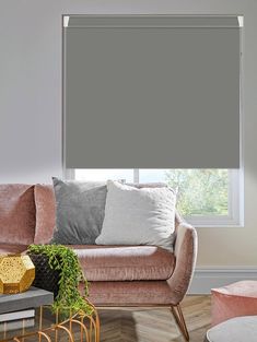 a living room with pink couches and grey shades on the window sill,