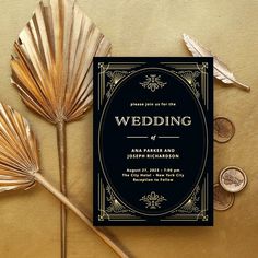 a black and gold wedding card next to some fan shaped coins on top of a table