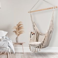 a hammock chair hanging from the ceiling in a bedroom with white walls and wood floors