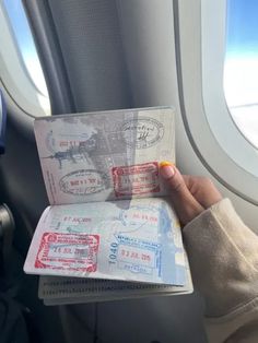 someone is holding their passport in front of an airplane window