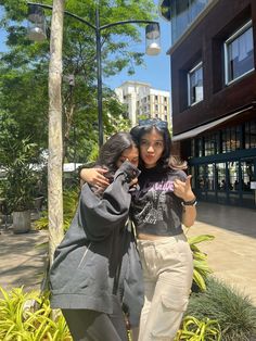 two young women standing next to each other on a sidewalk in front of a building