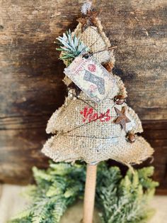 a small christmas tree made out of burlock and wood sticks on top of a wooden table