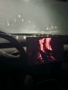 a car dashboard with a fire in the fireplace on it's display screen at night