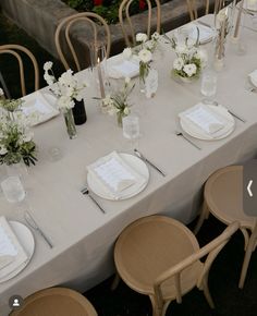 the table is set with white flowers and place settings