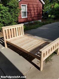 a wooden bed frame sitting in front of a house