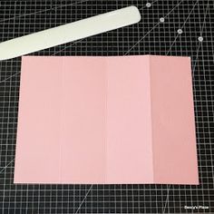 a piece of pink paper sitting on top of a cutting board