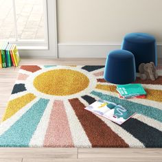 a colorful rug with two blue stools on the floor and a book in front of it