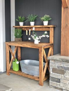 some potted plants are sitting on top of a wooden shelf next to a brick wall