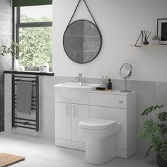 a bathroom with a toilet, sink and mirror on the wall next to a potted plant