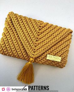 a yellow crochet purse with tassels and a tag on the front