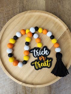 the trick or treat bracelet is decorated with black, orange and white beads on a wooden plate