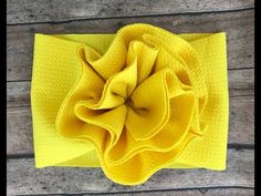 a yellow cloth flower on top of a wooden table