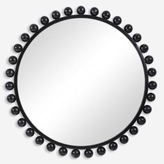 a round mirror with black balls around it