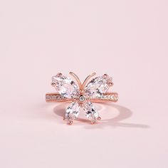 a rose gold ring with three diamonds on the band and an oval cut diamond in the center