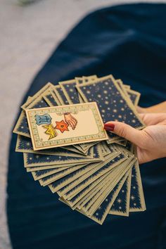 a person holding up some cards on top of a blue cloth covered table with white stars