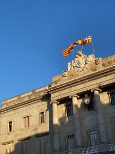 two flags are flying on top of a building