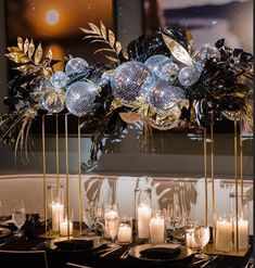 the centerpiece is decorated with silver balls and greenery, while candles are placed in front of it