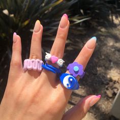 a woman's hand with three rings on it and two flowers in the middle