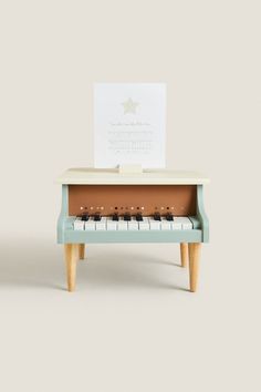 a toy piano sitting on top of a wooden table next to a sheet of paper