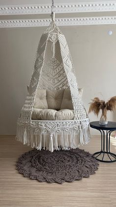 a white hammock chair sitting on top of a wooden floor next to a table