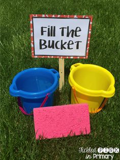 three buckets are sitting in the grass with a sign that says fill the bucket