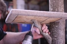 a man is working on a piece of wood with a drill and screwdriver